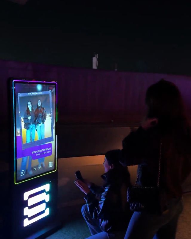 Guests pose at a FRXME photo booth at night at MDL Beast Soundstorm.